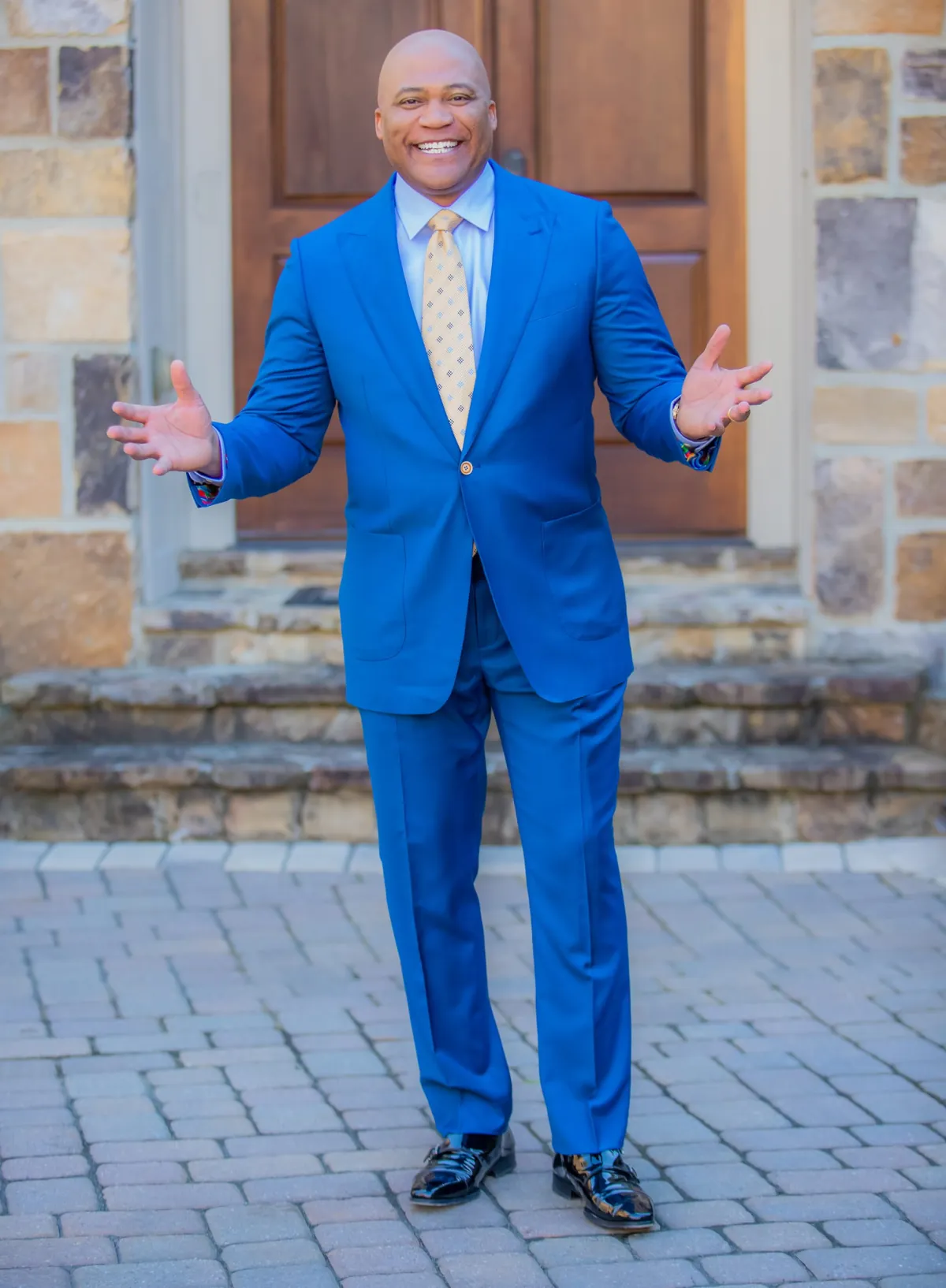 Dr. William A. Cooper smiling with arms open, wearing a blue suit